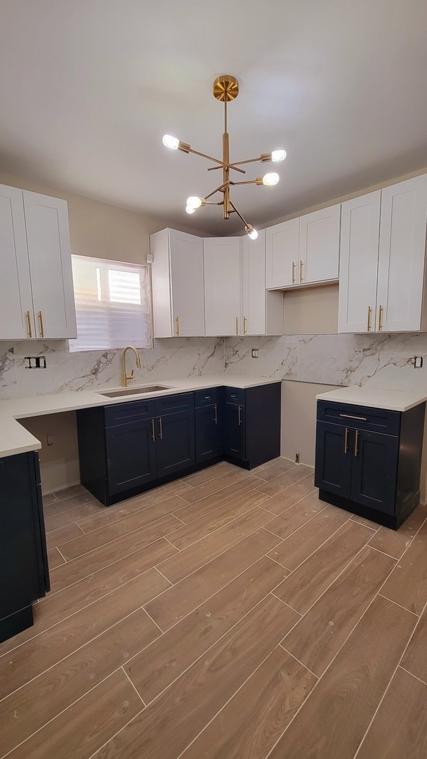 kitchen with white cabinets, light hardwood / wood-style floors, sink, and a chandelier