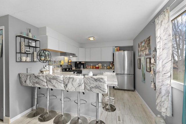 kitchen with exhaust hood, black appliances, a kitchen breakfast bar, kitchen peninsula, and white cabinetry