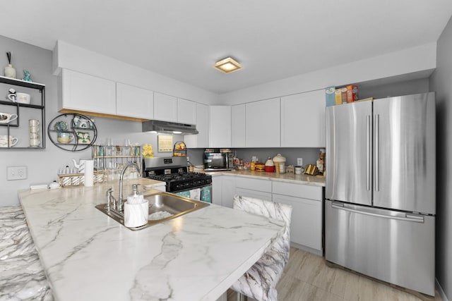 kitchen featuring appliances with stainless steel finishes, light stone counters, white cabinetry, and sink