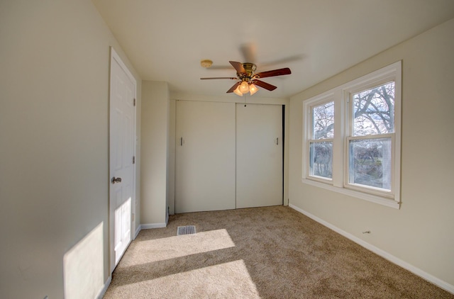 unfurnished bedroom with ceiling fan, light carpet, and a closet