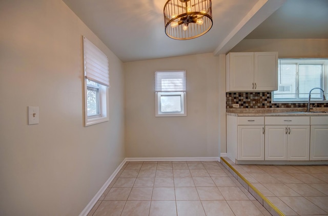 kitchen featuring backsplash, white cabinetry, sink, and an inviting chandelier