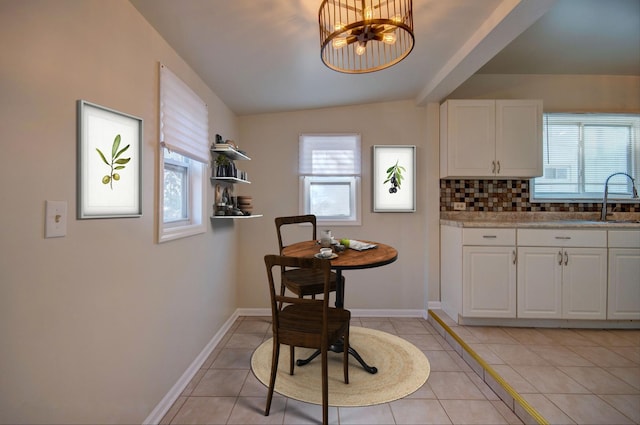 dining room featuring plenty of natural light, sink, light tile patterned floors, and lofted ceiling