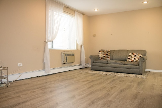 sitting room featuring light wood-type flooring, a wall unit AC, and a baseboard heating unit