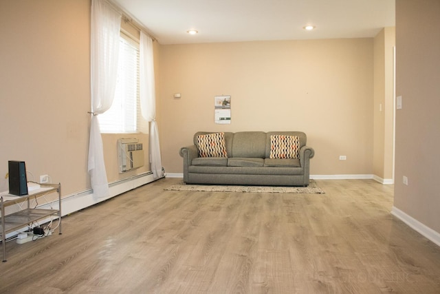 sitting room with a wall mounted air conditioner, light hardwood / wood-style floors, and a baseboard heating unit