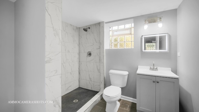 bathroom with a tile shower, vanity, and toilet