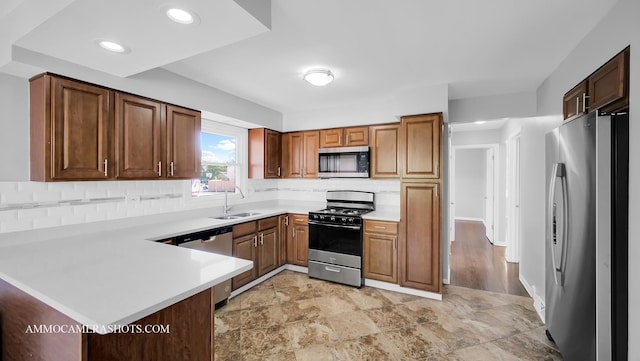 kitchen featuring sink, kitchen peninsula, stainless steel appliances, and tasteful backsplash