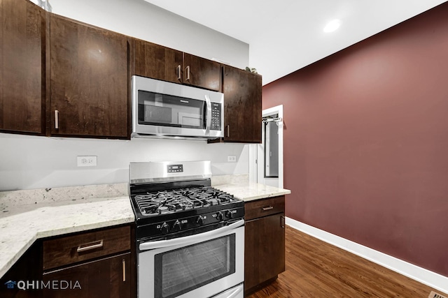 kitchen with dark brown cabinetry, light stone countertops, stainless steel appliances, and dark hardwood / wood-style floors