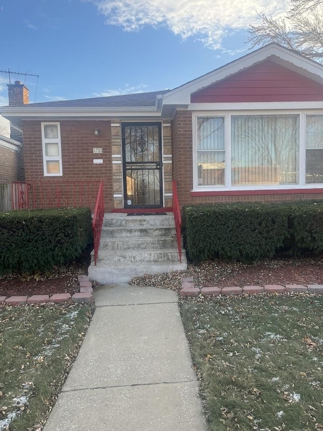 view of exterior entry featuring a lawn