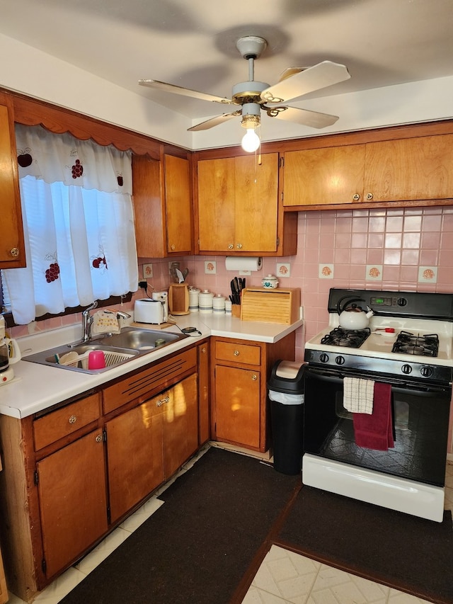 kitchen with white range with gas stovetop, tasteful backsplash, ceiling fan, and sink