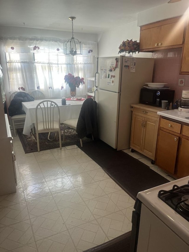 kitchen with decorative backsplash, white appliances, and decorative light fixtures