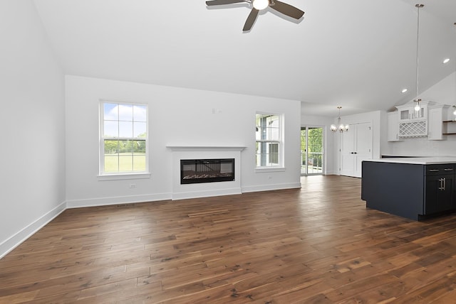 unfurnished living room with a wealth of natural light, dark hardwood / wood-style flooring, and ceiling fan with notable chandelier