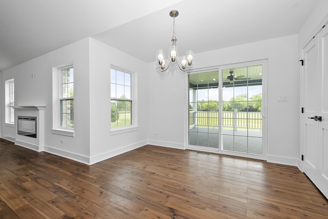 unfurnished dining area with ceiling fan with notable chandelier and dark hardwood / wood-style flooring