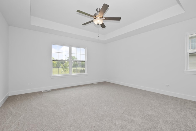 carpeted empty room featuring a tray ceiling and ceiling fan