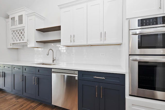 kitchen with backsplash, dark wood-type flooring, white cabinets, sink, and stainless steel appliances