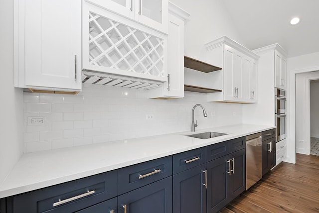 kitchen featuring white cabinetry, sink, stainless steel appliances, dark hardwood / wood-style floors, and backsplash