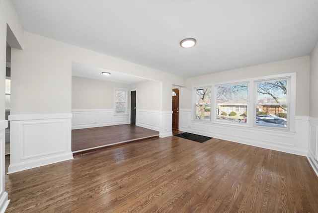 interior space with dark wood-style floors, wainscoting, and a healthy amount of sunlight