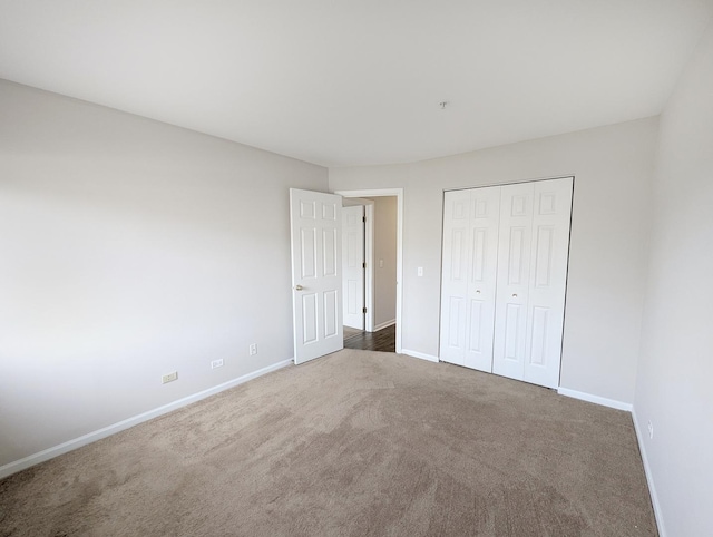 unfurnished bedroom with dark colored carpet and a closet