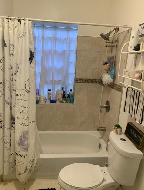 bathroom with tile patterned flooring, toilet, and shower / tub combo with curtain