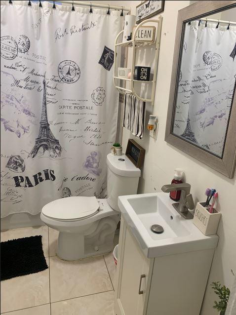 bathroom featuring tile patterned flooring, vanity, toilet, and curtained shower