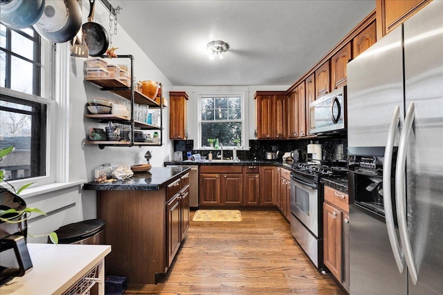 kitchen featuring tasteful backsplash, sink, light hardwood / wood-style floors, and appliances with stainless steel finishes