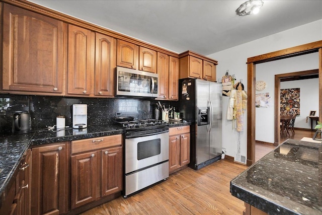 kitchen with decorative backsplash, appliances with stainless steel finishes, and light hardwood / wood-style flooring