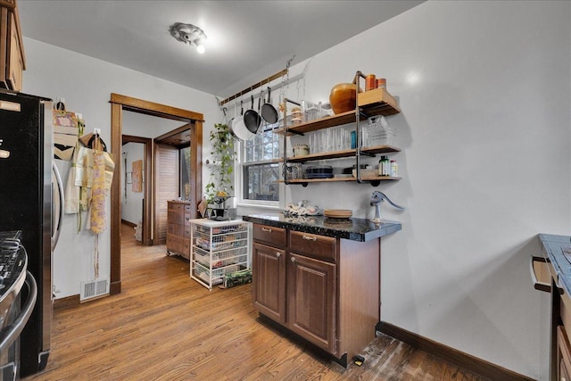 kitchen featuring dark brown cabinetry, light hardwood / wood-style flooring, and appliances with stainless steel finishes