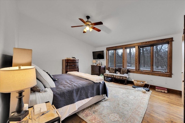 bedroom with ceiling fan, light hardwood / wood-style flooring, and vaulted ceiling