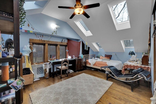 interior space featuring hardwood / wood-style flooring, ceiling fan, and lofted ceiling with skylight