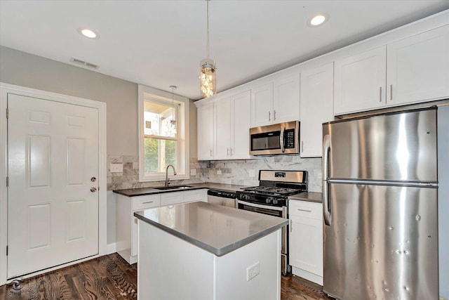 kitchen with sink, a center island, pendant lighting, white cabinets, and appliances with stainless steel finishes