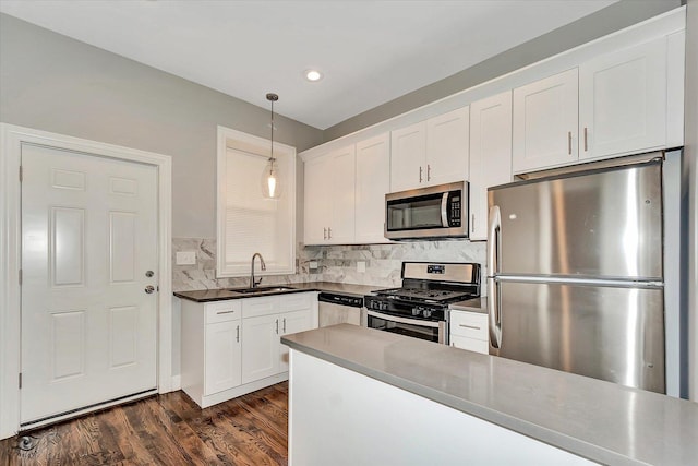 kitchen featuring sink, hanging light fixtures, dark hardwood / wood-style flooring, white cabinets, and appliances with stainless steel finishes