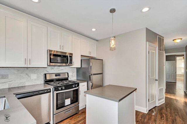 kitchen featuring pendant lighting, white cabinets, appliances with stainless steel finishes, a kitchen island, and dark hardwood / wood-style flooring