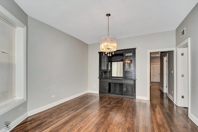 unfurnished living room with dark hardwood / wood-style floors and an inviting chandelier