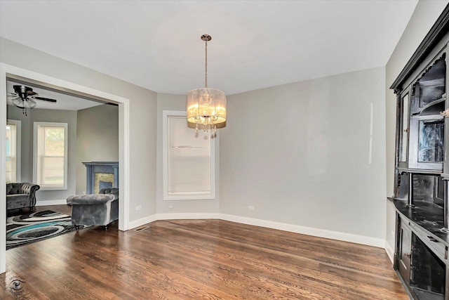 dining space featuring dark hardwood / wood-style floors and ceiling fan with notable chandelier