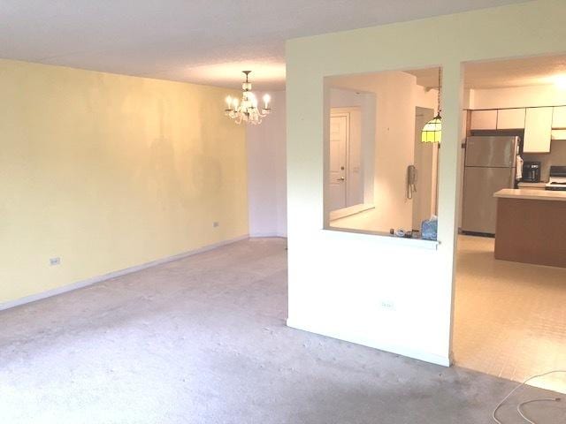 kitchen featuring stainless steel refrigerator, an inviting chandelier, pendant lighting, light carpet, and range