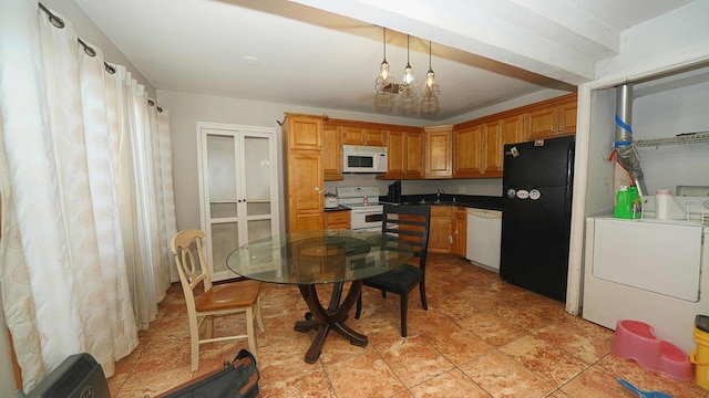 kitchen featuring washing machine and clothes dryer, sink, hanging light fixtures, and white appliances