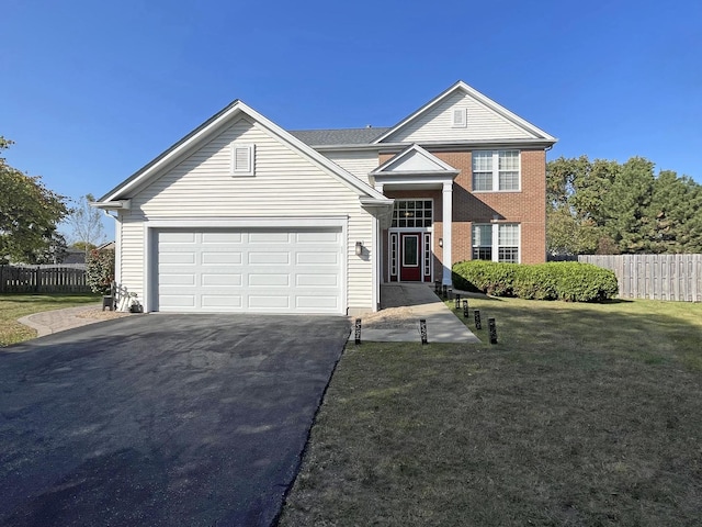 traditional home with fence, an attached garage, a front lawn, aphalt driveway, and brick siding