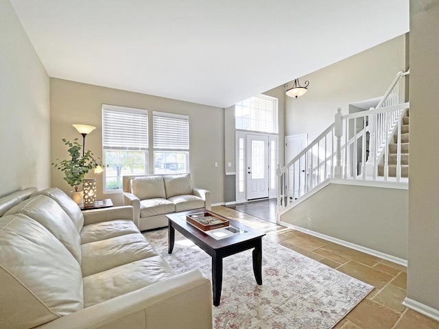 living area featuring stairway, plenty of natural light, and baseboards