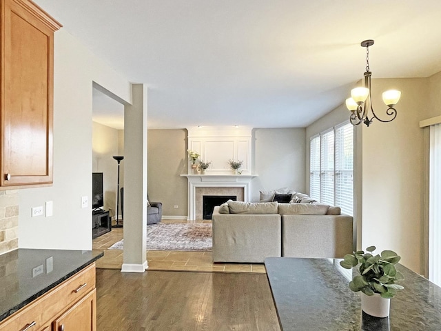 living area with baseboards, a large fireplace, a notable chandelier, and dark wood-style floors