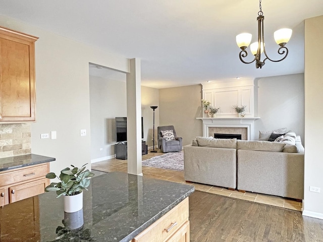 living room with a notable chandelier, a fireplace, baseboards, and wood finished floors