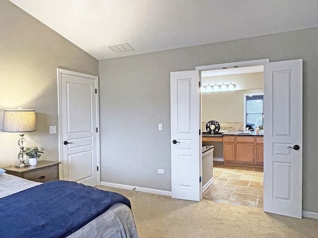 bedroom with connected bathroom, visible vents, baseboards, and light carpet