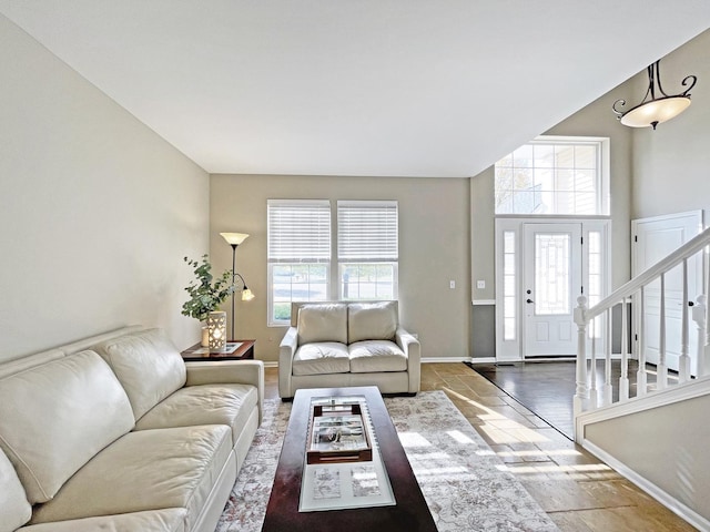 living room with a wealth of natural light, baseboards, stone tile floors, and stairs