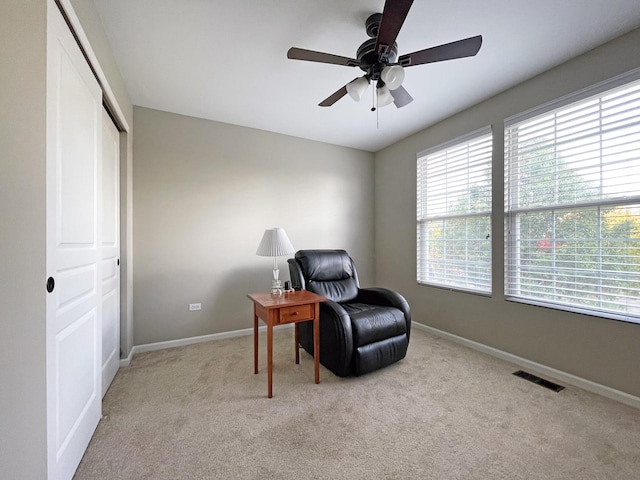 living area with visible vents, baseboards, light carpet, and ceiling fan