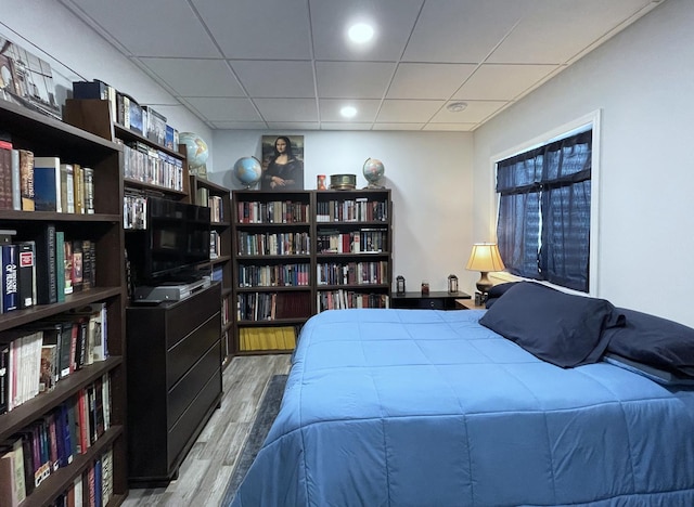 bedroom featuring a drop ceiling and wood finished floors