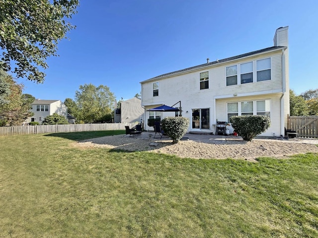 back of property featuring a yard, a patio area, fence, and a chimney