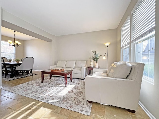 living room with a chandelier, baseboards, and stone tile flooring