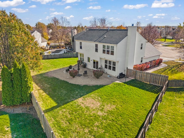 back of property with roof with shingles, a lawn, a chimney, a fenced backyard, and a patio area