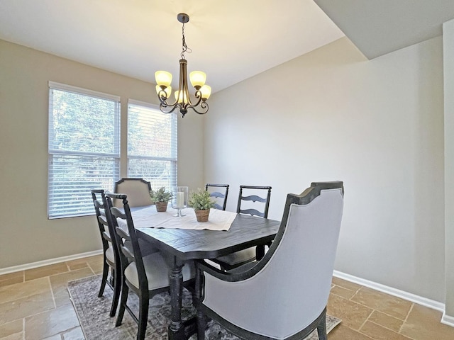 dining area featuring stone tile flooring, a chandelier, and baseboards