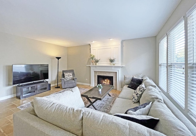 living room featuring stone tile floors, a fireplace, and baseboards