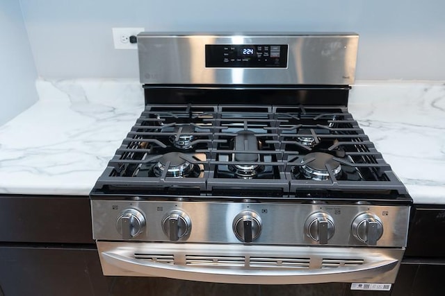 room details with light stone counters and stainless steel range with gas stovetop