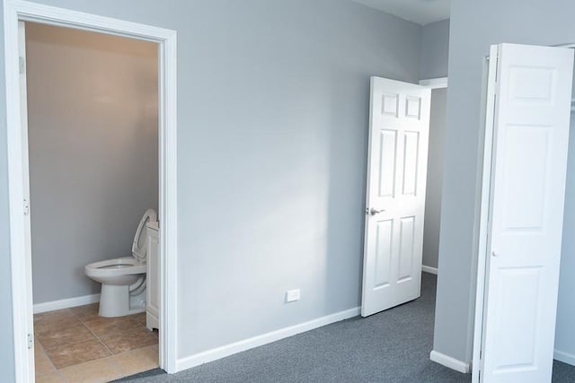 unfurnished bedroom featuring connected bathroom and dark carpet